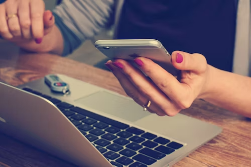 A woman holding an iphone with mac in front of her
