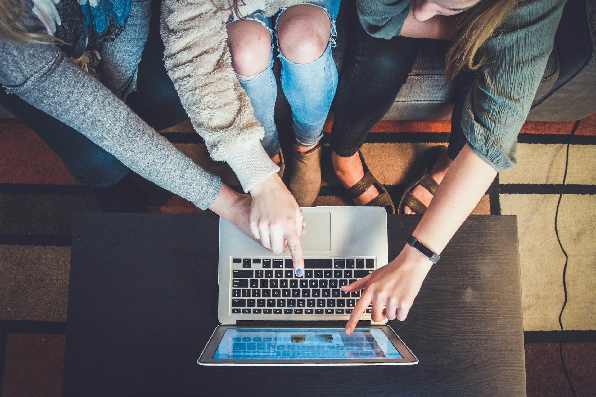 Three person pointing on a laptop