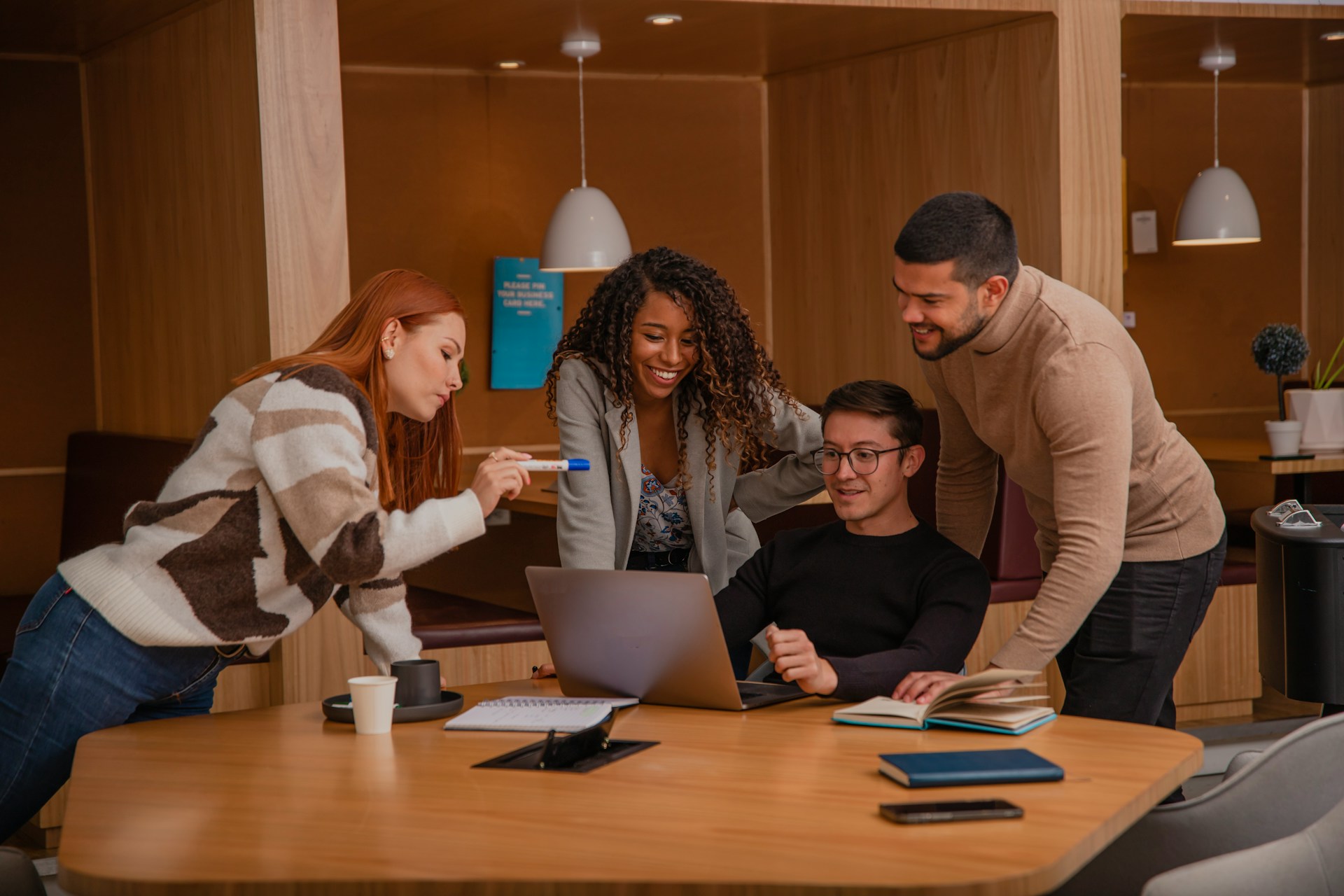Group of people standing around one guy with a laptop