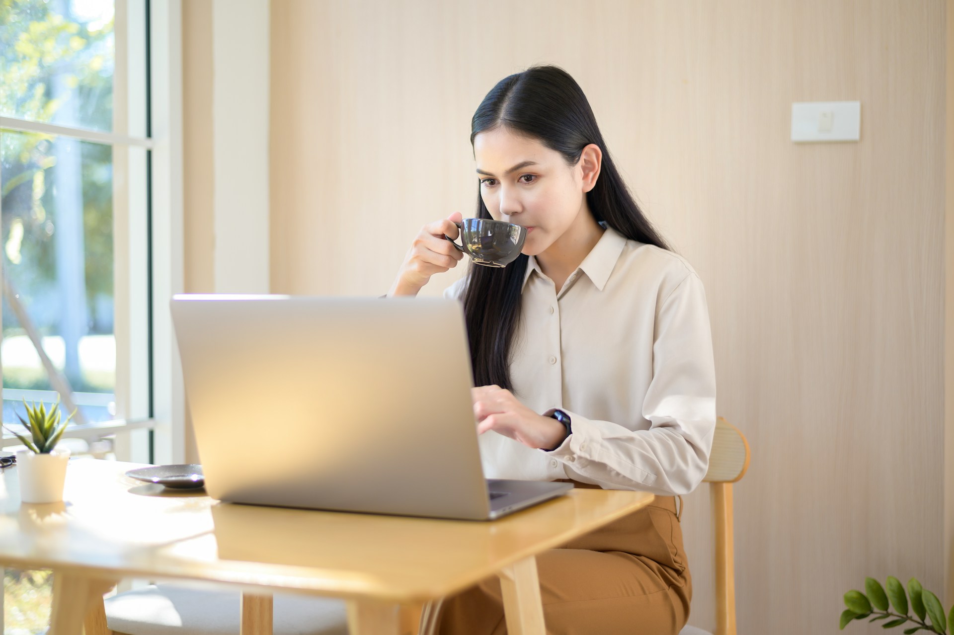 Woman using her laptop while sipping coffee